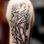 Фото тату ангела с распростертыми крыльями на плече. Изящный рисунок в черно-серых тонах, подчеркивающий красоту и свободу.