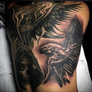 Фото тату на всю спину и бок: ангел с распростертыми крыльями, череп и темные тени. Реалистичный рисунок татуировки в черно-серых тонах.