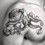 Фото тату осьминога на плече и груди. Реалистичный рисунок, черно-белая графика, осьминог держит черепа.