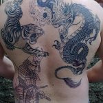 Фотография большой татуировки на спине, изображающей тигра, дракона, самурая и символ Инь-Янь. Черно-серый рисунок с множеством деталей.
