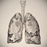 Фото татуировки с изображением легких, внутри которых различные символы: бабочки, цветы, надписи. Черно-белый стиль, детализированная проработка.
