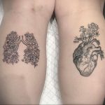 Фото тату на бедрах: реалистичное изображение сердца и легких, украшенных цветами. Детализированный рисунок татуировки, выполненный в черных тонах.
