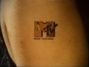 Фото тату логотипа MTV на теле. Черно-белый рисунок татуировки, выполненный в минималистичном стиле, расположен на боку.