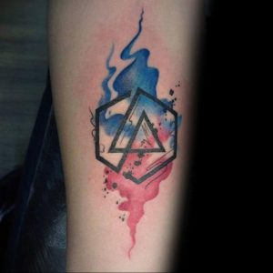 Фото тату на руке: акварельная татуировка с логотипом группы Linkin Park, выполненная в синих и красных тонах. Яркий и современный дизайн.