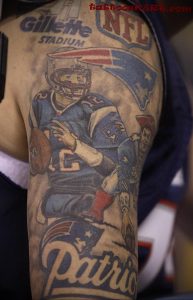 Фото татуировки на руке с изображением игрока в американский футбол, логотипа NFL и надписи 'Gillette Stadium'.