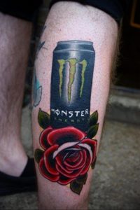 Фото тату на ноге: банка Monster Energy с логотипом и красная роза. Реалистичный стиль, яркие цвета, детализированный рисунок.