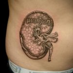 Фото татуировки почки на боку, выполненной в стиле дотворк с греческой надписью и точечным узором.