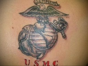 Фото тату на спине с изображением эмблемы Корпуса морской пехоты США (USMC). Классический рисунок татуировки в черно-красных тонах.