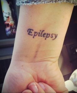 Фото тату: надпись 'Epilepsy' нанесена на запястье. Простой и лаконичный рисунок татуировки.