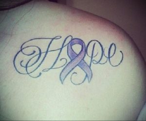 Фото татуировки на плече: изящная надпись 'Hope' с фиолетовой лентой, символизирующей надежду и поддержку. Красивый и вдохновляющий рисунок.
