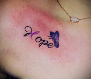 Фото татуировки с надписью 'Hope' и изображением фиолетовой бабочки. Нежный дизайн, пастельные тона, женственный стиль. Идея для тату, символизирующей надежду и возрождение.