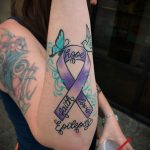 Фото тату на предплечье: фиолетовая лента, бабочка, птица и надписи 'hope', 'faith', 'love', 'Epilepsy'. Символизирует поддержку и борьбу с эпилепсией.