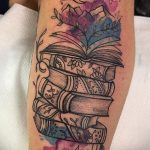 Фото тату на руке: стопка книг, цветы, луна, акварельный стиль, пастельные тона. Красивая и нежная татуировка.