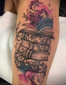 Фото тату на руке: стопка книг, цветы, луна, акварельный стиль, пастельные тона. Красивая и нежная татуировка.