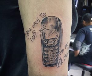 Фото тату: старый кнопочный телефон с надписью "You used to call me on my cell phone". Рисунок выполнен в черно-белом стиле.