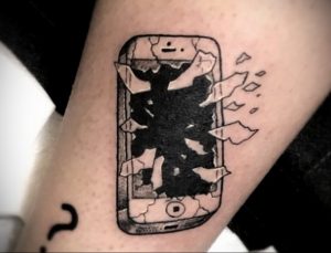 Черно-белое фото татуировки на руке с изображением разбитого экрана смартфона iPhone. Реалистичный рисунок татуировки, передающий ощущение хрупкости.