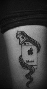 Черно-белое фото тату на ноге с изображением змеи, обвивающей смартфон iPhone. Стильный и необычный рисунок татуировки.