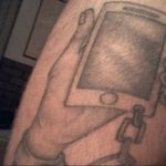 Фото тату телефона, держащегося рукой, с цепью, символизирующей зависимость, выполненное в черно-белой графике.