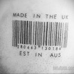 Фото тату штрихкода с надписями 'Made in the UK' и 'Est in AUS' на спине человека. Черно-белый рисунок татуировки.