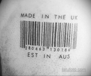 Фото тату штрихкода с надписями 'Made in the UK' и 'Est in AUS' на спине человека. Черно-белый рисунок татуировки.