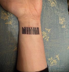 Фото тату на запястье: простой черный штрих-код с цифрами, выполненный в минималистичном стиле, лаконичный рисунок татуировки.