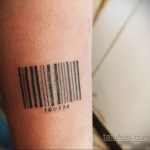 Фото тату на руке: небольшой черный штрих-код с цифрами, выполненный в минималистичном стиле, лаконичный рисунок татуировки.