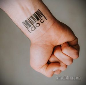 Фото тату на запястье: простой штрих-код с надписью 'doc', выполненный в черном цвете, лаконичный рисунок татуировки.