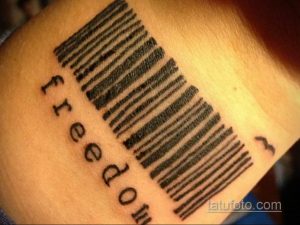 Фото татуировки штрих-кода с надписью "freedom" и изображением летящей птицы. Черно-белый рисунок на руке, символизирующий свободу.