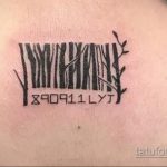 Фото татуировки штрих-кода, из которого растут ветви дерева. Черно-белый рисунок на плече, символизирующий связь с природой.