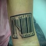 Фото тату на предплечье: штрихкод, разорванный острым когтем, с надписью 'not defined by labels'. Символизирует отказ от социальных ярлыков.