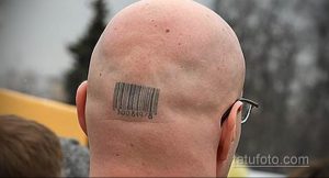 Фото тату штрих-кода на затылке лысого мужчины. Черный рисунок татуировки выглядит как стандартный код, нанесенный на кожу.
