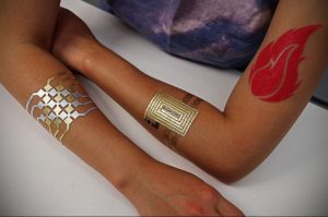 Фото тату с геометрическими узорами на руках. Золотые, серебряные и красные элементы татуировки.
