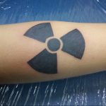 Фото тату: минималистичный рисунок знака радиации, выполненный черными чернилами на руке. Подходит для тех, кто ценит лаконичность и символизм.