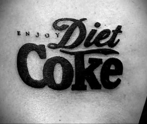 Черно-белое фото татуировки на руке с изображением логотипа Diet Coke.