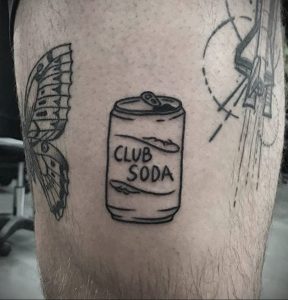 Черно-белое фото татуировки на ноге с изображением банки Club Soda, выполненной в простом стиле.