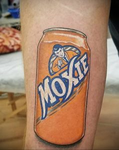 Фото тату: реалистичный рисунок банки газировки Moxie на мускулистой руке, выполненный в ярких оранжевых и синих тонах. Идеально для любителей ретро-эстетики.
