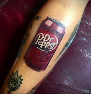 Фото тату реалистичной банки Dr Pepper на предплечье. Красный цвет, детальная прорисовка логотипа и бликов.