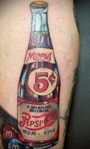 Фото тату старинной бутылки Pepsi с надписью 'Mom' и ценой '5¢'. Красный, белый и желтый цвета, ретро-стиль.