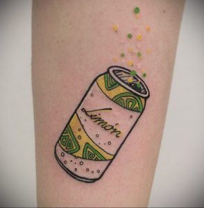 Фото тату банки лимонада с надписью 'Limon'. Желтый, зеленый и черный цвета, динамичный рисунок.