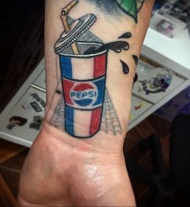 Фото тату в стиле олдскул стакана Pepsi с трубочкой и брызгами. Красный, белый и синий цвета, четкие контуры.