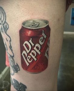 Фото тату реалистичной банки Dr Pepper на предплечье. Красный цвет, детальная прорисовка логотипа и бликов.
