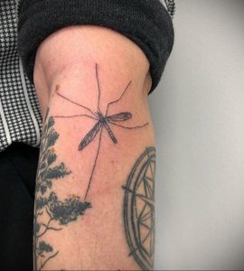 Черно-белая татуировка комара на предплечье, выполненная в минималистичном стиле. Тонкие линии и лаконичный дизайн.