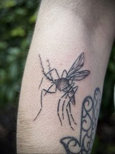 Черно-белая татуировка комара на руке, выполненная в минималистичном стиле. Тонкие линии и лаконичный дизайн.