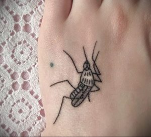Небольшая черно-белая татуировка комара на стопе. Лаконичный рисунок с четкими линиями, выполненный в стиле минимализм.