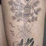 Фото татуировки на ноге, изображающей дерево жизни, корни которого переходят в спираль ДНК, удерживаемые руками, выполненное в технике дотворк.