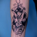 Черно-белое фото тату на предплечье с изображением Sailor Moon, связанной веревками. Детализированный рисунок в стиле аниме, подчеркивающий хрупкость и силу.