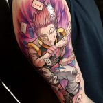 Фото татуировки Киллуа Золдика из аниме Hunter x Hunter на плече. Детализированный рисунок с использованием ярких цветов и изображением игральных карт.