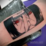 Фото татуировки на руке с изображением Итачи Учиха из аниме Naruto. Черно-белый рисунок с акцентом на глаза и детали лица.