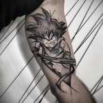 Фото тату на руке с изображением Гоку из Dragon Ball Z в момент концентрации, выполненное в черно-белом стиле.