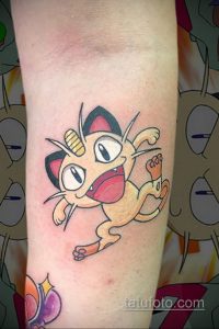 Фото тату с изображением Meowth из Pokemon, выполненное в ярких цветах на руке.